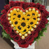 Heart-shaped arrangement of red roses, yellow sunflowers, and gold-wrapped chocolates