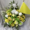 Yellow and white floral arrangement with golf balls and a small flag