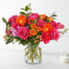 Pink and orange mixed flower bouquet in a clear glass vase