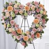 Heart-shaped floral wreath on an easel with pink, peach, and lavender blooms