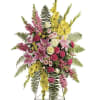Standing floral spray with pink, yellow, and white flowers on an easel