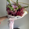 Pink mixed flower bouquet wrapped in white paper with a pink ribbon