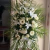 White funeral spray with lilies, gerberas, and palm fronds