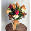 Mixed bouquet of orange lilies, pink roses, and white carnations in a glass vase