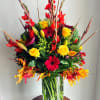 Tall mixed bouquet in a glass vase with red, yellow, and orange flowers