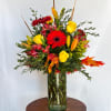 Mixed bouquet of red and yellow flowers in a tall glass vase