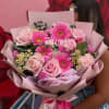 Pink bouquet of roses and gerbera daisies wrapped in pastel paper
