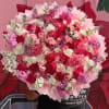 Large bouquet of pink, red, and white flowers wrapped in pale pink paper