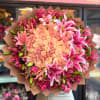 Large bouquet of pink roses and lilies wrapped in brown paper