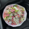 Large bouquet of pink, white, and green flowers wrapped in pale pink mesh