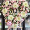 Heart-shaped floral wreath with pink and white flowers on an easel