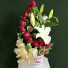 Red roses and white lilies in a festive holiday container with a gold bow