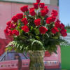 Tall vase arrangement of red roses with fern foliage