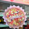 Large pastel bouquet of roses, carnations, and small daisies wrapped in pink paper