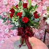Red roses in a glass vase with a plaid ribbon