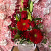 Red roses and gerbera daisies arranged in a clear glass vase