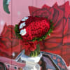 Heart-shaped bouquet of red roses with white flowers and a red ribbon