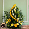 Yellow and white rose arrangement in a square vase with a plush pug beside it
