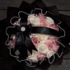 Bouquet of pink and white roses wrapped in black paper with a satin bow