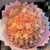Large bouquet of pastel roses wrapped in pink paper with a decorative crown