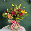 Bouquet of red roses, yellow lilies, and peach flowers tied with a gingham ribbon