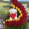 Red and yellow rose arrangement with a teddy bear holding a heart