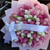 Bouquet of pink and white tulips wrapped in pale pink paper with a white ribbon