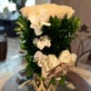 White roses and orchids in a tall arrangement with a striped ribbon bow.