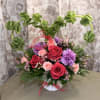 Heart-shaped floral arrangement with roses and purple carnations