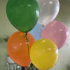 Cluster of colorful helium balloons in green, white, pink, orange, and yellow