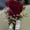 Single red rose with small white filler flowers in a clear glass vase