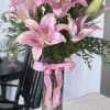 Pink lilies in a clear glass vase tied with a pink polka-dot ribbon.