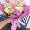 Pink and peach mixed bouquet wrapped in magenta paper with a ribbon
