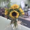 Sunflower bouquet in a clear glass vase with raffia tie