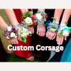 Group of floral corsages on wrists with white roses and ribbons