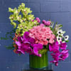 Pink roses and orchids arranged in a green glass vase