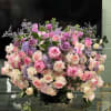Large arrangement of pink, lavender, and cream roses in a black vase