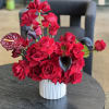 Red rose arrangement with dark calla lilies in a white vase