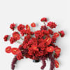 Red floral arrangement with roses and anthuriums in a dark vase