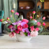 Pink and lavender floral arrangement in a white bowl vase