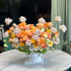 Peach and cream rose arrangement in a white pedestal vase