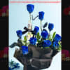 Bouquet of blue roses wrapped in black paper with a bottle centerpiece