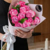 Bouquet of pink roses wrapped in pale paper with a white ribbon