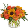 Orange roses and sunflowers in a clear glass vase