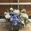Blue hydrangeas and white roses arranged in a glass vase