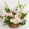 Pastel pink and white flower basket with roses, snapdragons, and other blooms in a woven wicker basket