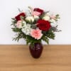 Bouquet of red and white roses with pink carnations in a burgundy vase