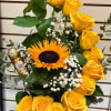 Yellow roses and a sunflower in a white basket with chocolates