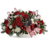 Red roses and white flowers in a low holiday centerpiece with candy canes and pinecones