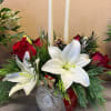 Holiday floral centerpiece with white lilies, red roses, and two taper candles